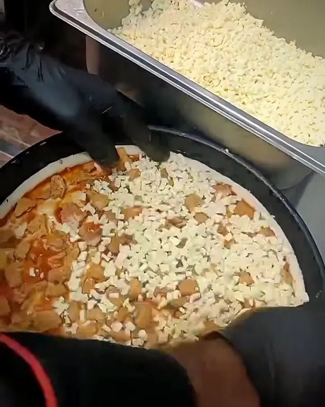 Cheese spread by hand over a pizza base